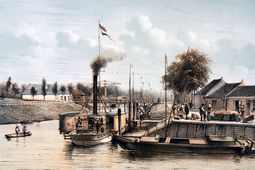 Aanlegplaats van de stoomvaartdienst op de Zuid-Willemsvaart in Den Bosch. Stoomboten speelden gedurende de negentiende eeuw bij het vervoer in ons waterrijke land een belangrijke rol. Voordat de meeste spoorwegen tot stand kwamen (1860-1875), was ons land door een uitgebreid netwerk van stoomvaartdiensten ontsloten. Daarna onderhielden stoomboten de verbindingen met afgelegen plaatsen. De afgebeelde stoomboot verzorgde het vervoer van passagiers en expresgoederen over de Zuid-Willemsvaart van ’s-Hertogenbosch naar Maastricht. De stoomboot ligt al onder stoom, gereed voor het vertrek. Rechts een vaartuig dat op sleeptouw kon worden genomen, wanneer veel goederen moesten worden vervoerd.