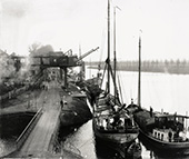 Overslag van suikerbieten bij de suikerfabriek van Sas van Gent aan het Kanaal van Gent naar Terneuzen, circa 1950. Voor het lossen van de schepen werden grote kranen gebruikt, die de overslagkosten aanzienlijk verminderden. Overslagkosten vormden in de concurrentie met het weg- en railvervoer een belangrijke factor.