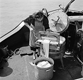 Leven aan boord van een Rijnschip. De vrouw van schippersknecht Van Geijn mangelt de was aan boord van de <em>Damco 203</em>, een groot sleepschip op de Rijn in Duitsland.