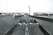 Invaart van een vierbaksduwstel in de Hartelsluizen bij Rotterdam, circa 1976. De Hartelsluizen vormden de verbinding tussen de Oude Maas en het Hartelkanaal bij Rotterdam. In 1982 werd het Hartelkanaal in open verbinding met de Oude Maas gebracht en daarmee verloren de sluizen hun functie. Vooral bij harde zijwind vereiste het veel stuurmanskunst om een ongeladen duwstel dat toen nog niet over koproeren of boegschroeven beschikte een sluis in te manoeuvreren.