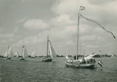 Admiraalzeilen door ronde- en platbodemjachten op het Pikmeer bij Grouw, 1953. Een eskader boeiers passeert het admiraalschip. Het Admiraalzeilen was onderdeel van de eerste reünie van de nog bestaande Friese ronde jachten, die de zeilvereniging ‘Oostergoo’ op verzoek van de commissie ‘Stamboek Friesche ronde jachten’ organiseerde.
